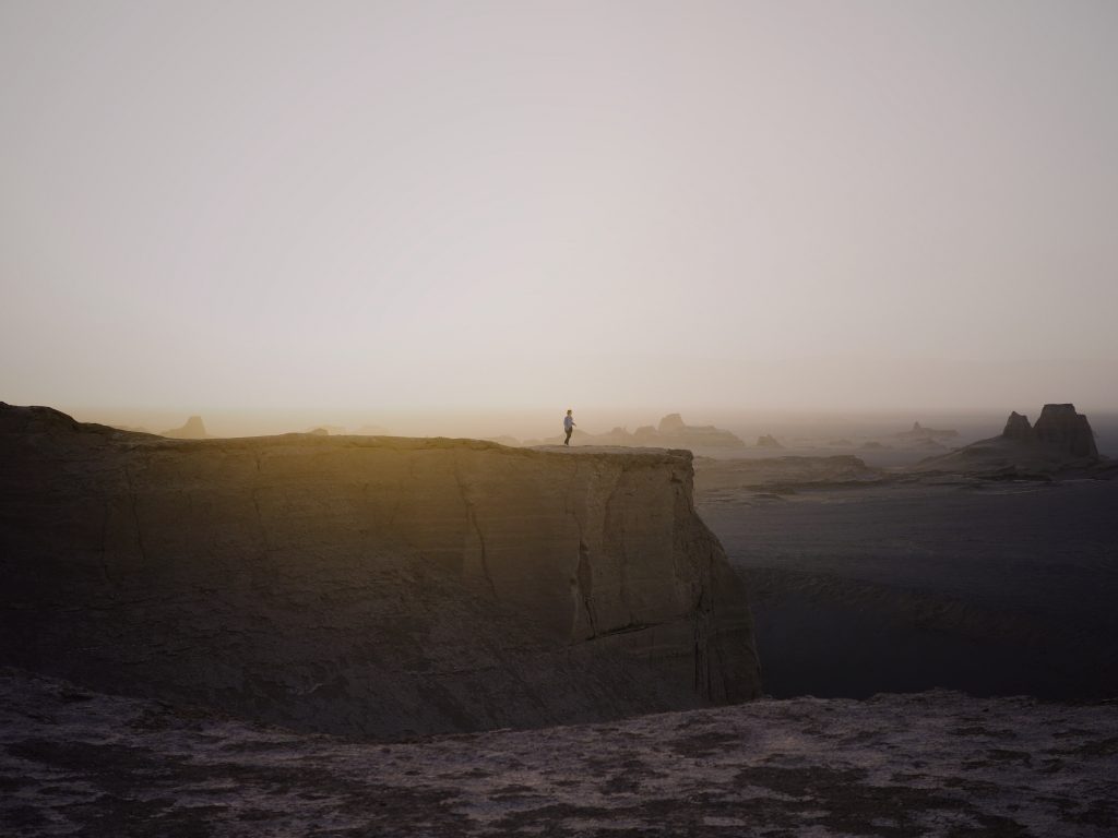 A man stands on the yardangs in the Lut Desert